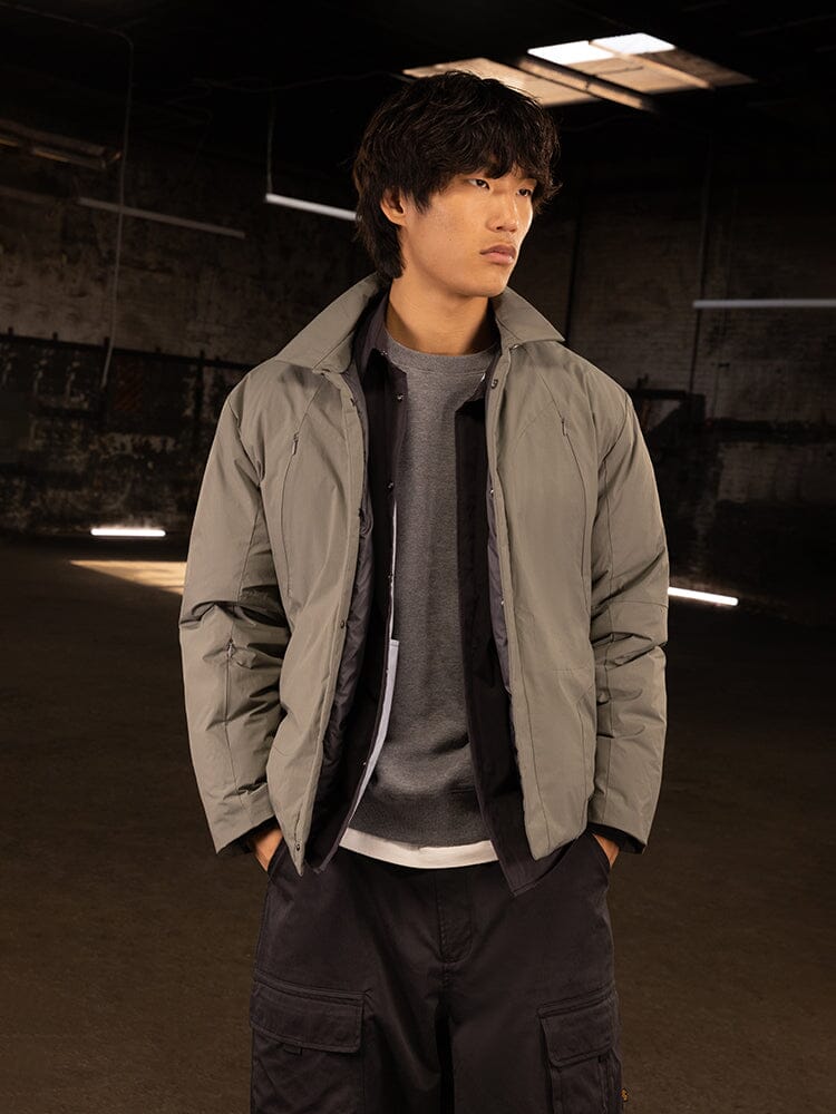 A person in an Alpha Industries FW24-Drop3-Recn Insulated Shirt Jacket, paired with dark pants, captures a streetwear vibe as they stand casually with hands in pockets.