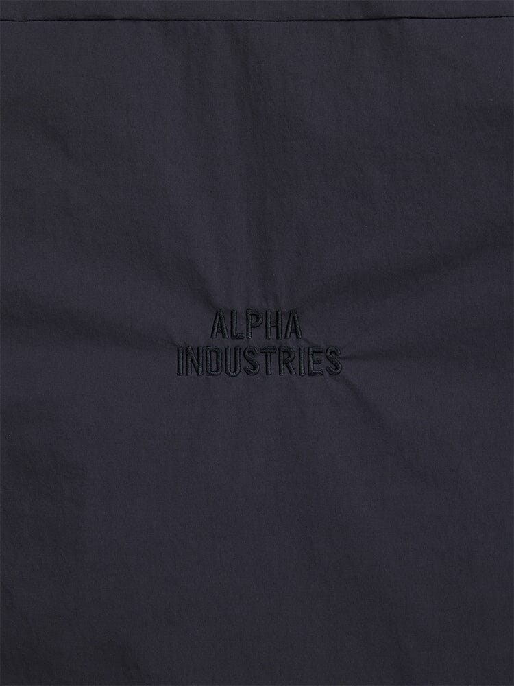 Close-up of a dark fabric with "Alpha Industries" embroidered in the center, highlighting the streetwear style of the Insulated Shirt Jacket.
