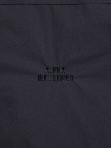 Close-up of a dark fabric with "Alpha Industries" embroidered in the center, highlighting the streetwear style of the Insulated Shirt Jacket.