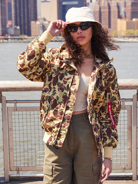 A person sporting the Alpha Industries, Inc. L-2B Hooded Gen II Bomber Jacket, along with khaki pants, sunglasses, and a white bucket hat, is highlighting their style with this lightweight hooded jacket.