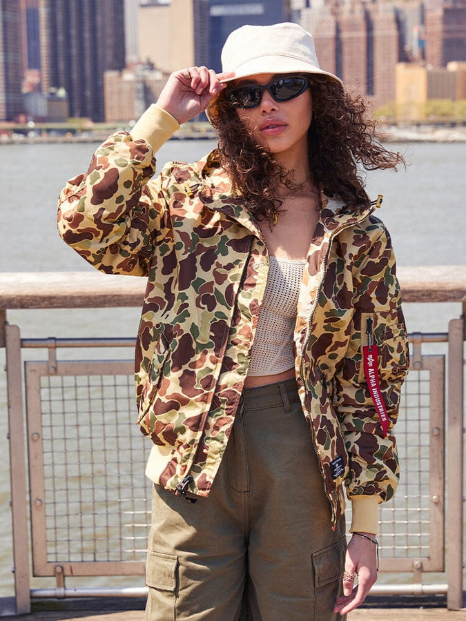 A person sporting the Alpha Industries, Inc. L-2B Hooded Gen II Bomber Jacket, along with khaki pants, sunglasses, and a white bucket hat, is highlighting their style with this lightweight hooded jacket.