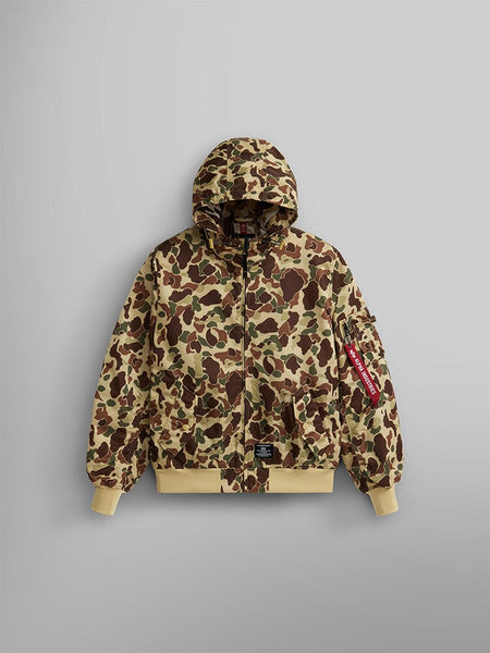 Alpha Industries, Inc.'s L-2B Hooded Gen II Bomber Jacket in Green Frogskin Camo is a nylon flight jacket with a hood, featuring ribbed cuffs and hem, and a red tag on the sleeve.