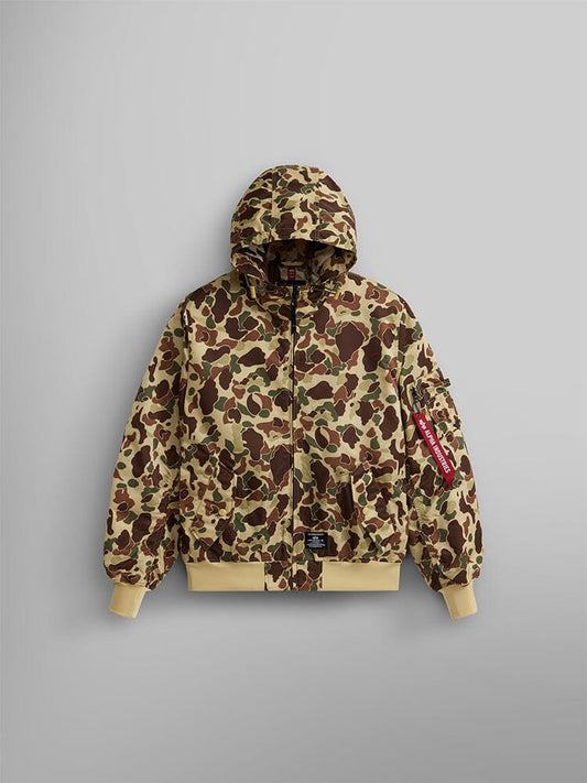 The L-2B Hooded Gen II Bomber Jacket by Alpha Industries, Inc. is a camouflage-patterned flight jacket in Green Frogskin Camo made from water-resistant nylon. It features a front zipper, beige cuffs, and a distinctive red tag on the sleeve.
