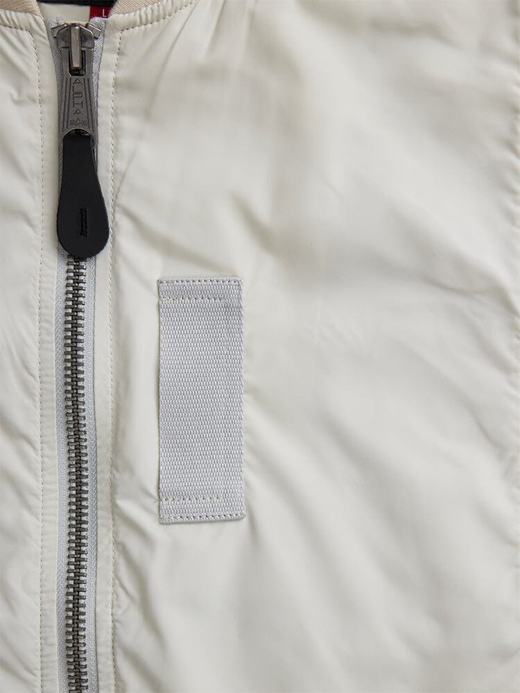 Alpha Industries L-2B Paratrooper Flight Jacket, white bomber with vertical silver zipper and rectangular gray fabric patch on front.