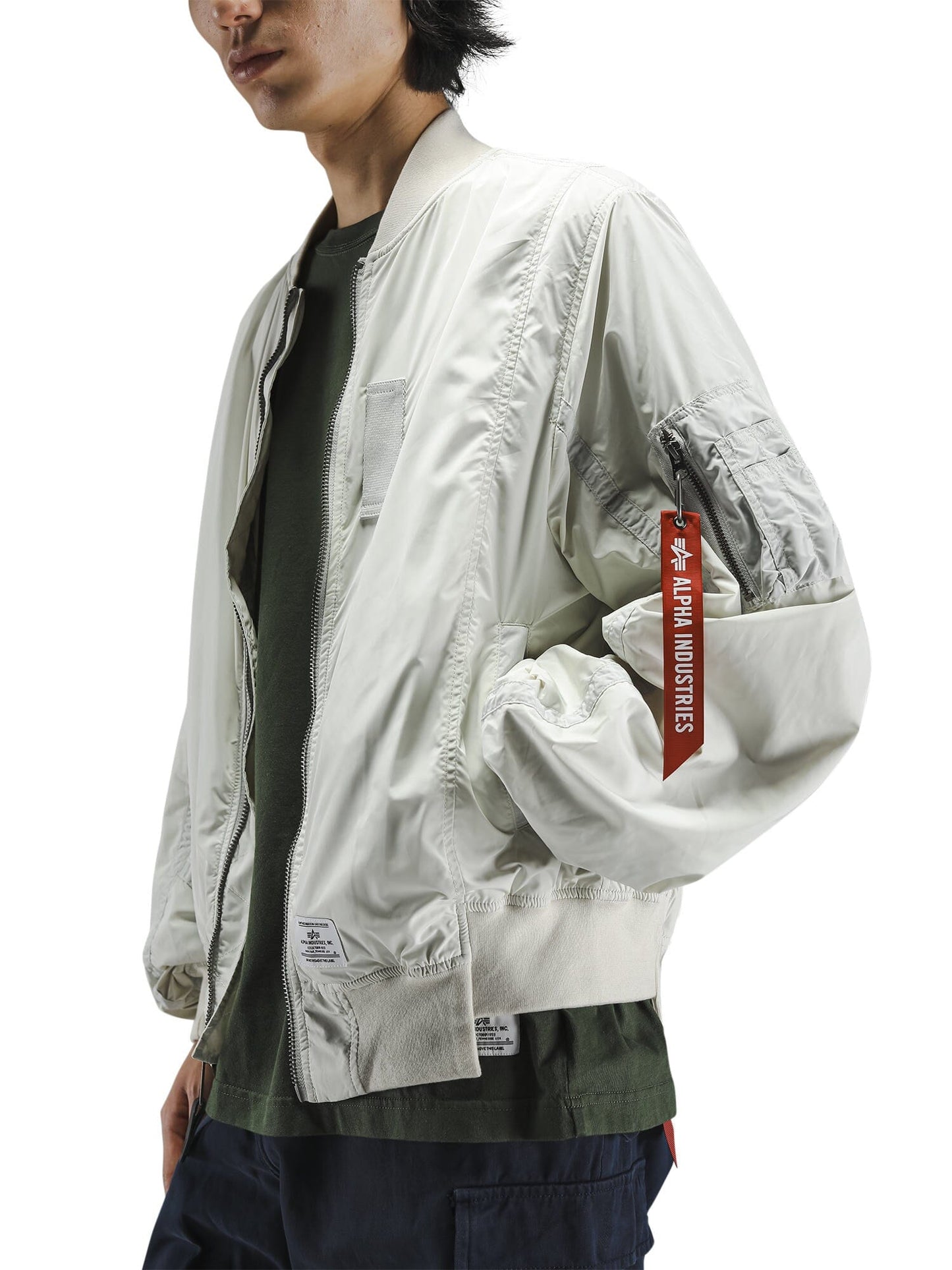 Alpha Industries L-2B Paratrooper Flight Jacket, light-colored bomber, asymmetrical hem, red Remove Before Flight tag.