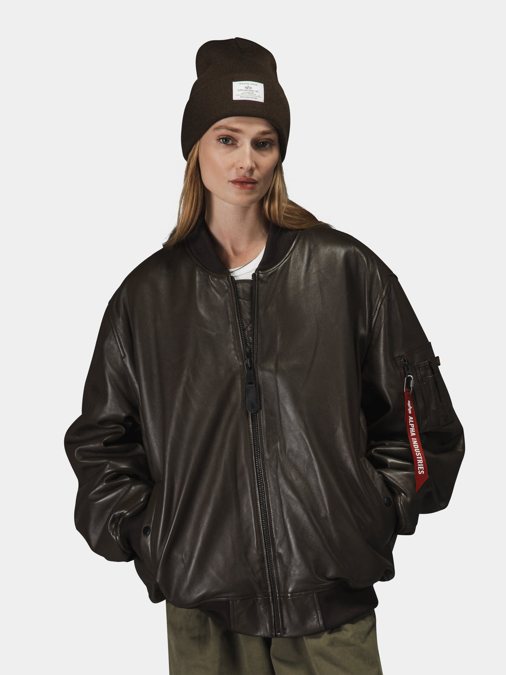 Alpha Industries Leather MA-1 Flight Jacket with zip closure, olive green pants, brown beanie with white label.