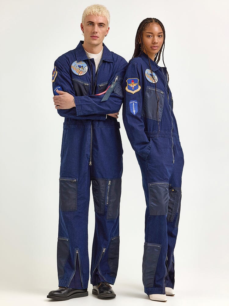 Two individuals clad in indigo Alpha Industries x Lee Flight Suits, crafted from ripstop cotton, stand side by side, radiating a vibe of performance fashion.