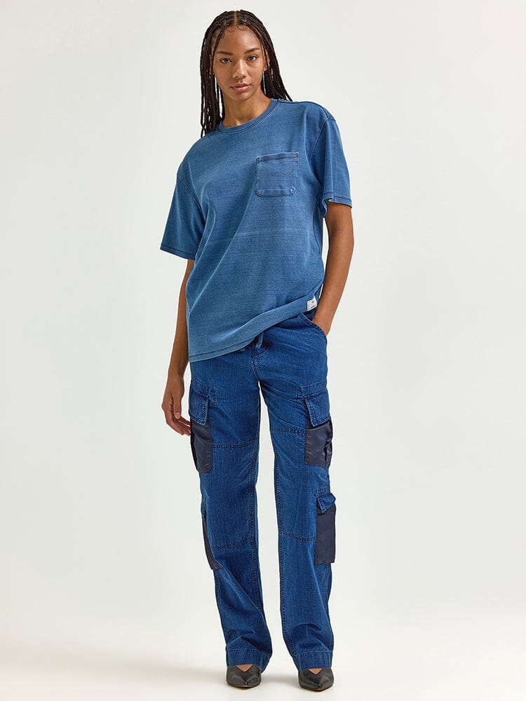 Clad in an Alpha Industries / FW24-Lee Looser Fit Indigo Dyed Tee and blue cargo pants featuring reinforced pockets, a person stands.