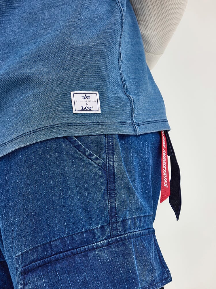 The indigo-dyed blue jeans, featuring a tag and branded label, pair perfectly with the Alpha x Lee Looser Fit Indigo Dyed Tee. The ensemble is enhanced with a reinforced pocket for added durability.