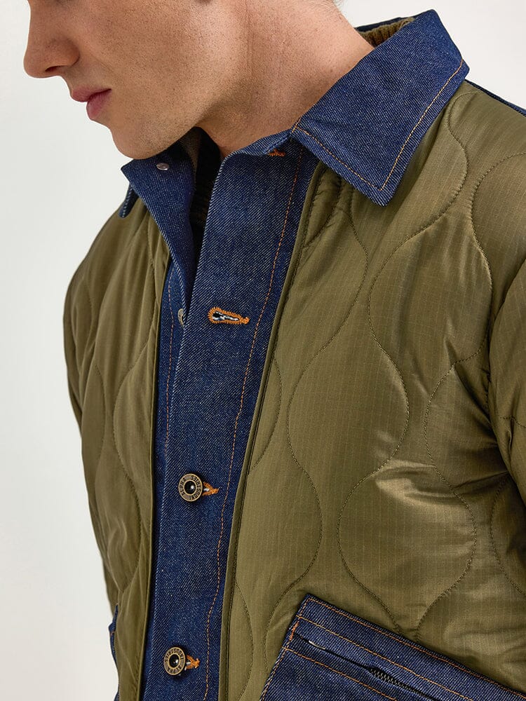 An up-close view of someone wearing the Alpha X Lee Quilted Jacket by Alpha Industries, highlighting its denim accents and wooden buttons, captures a heritage style through a mixed-media design.