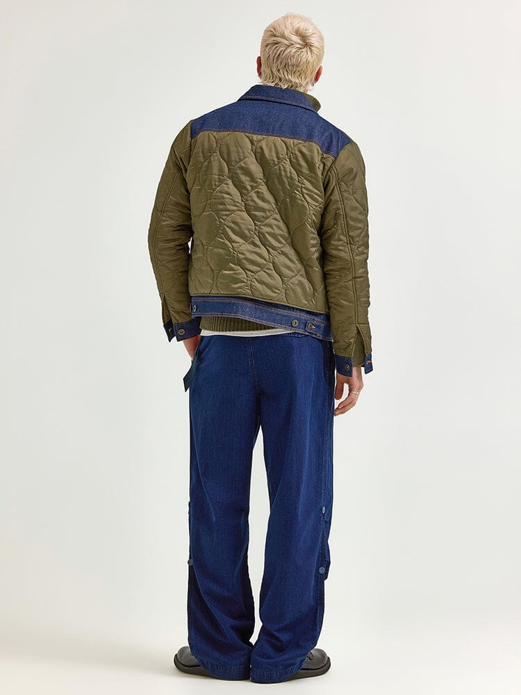 A person is wearing an Alpha X Lee Quilted Jacket from Alpha Industries, effortlessly embodying a mixed-media approach with blue denim pants and black shoes, standing with their back facing the camera.