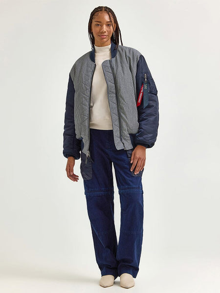 A person wearing an Alpha X Lee Reversible MA-1 Jacket over a white shirt, navy blue pants, and white shoes.