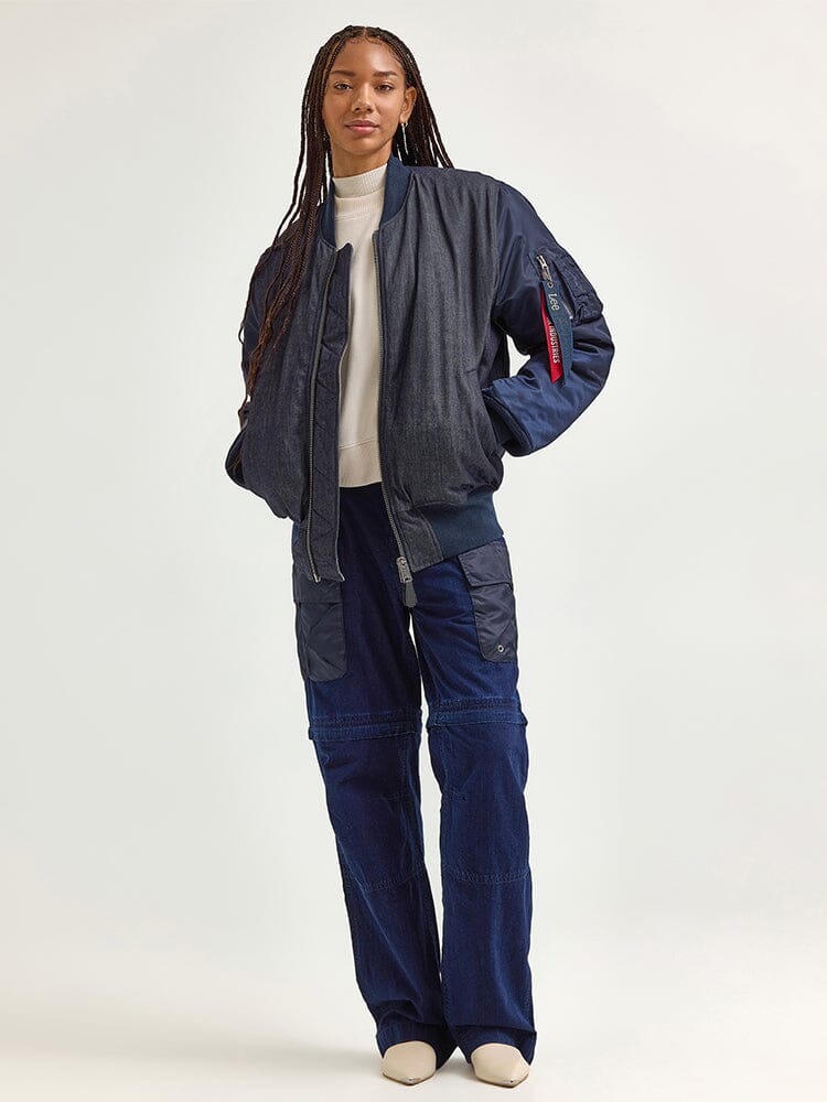 Wearing the Alpha X Lee Reversible MA-1 Jacket by Alpha Industries over a white turtleneck, paired with dark cargo pants and cream shoes, the person exudes a contemporary style infused with vintage railroad-stripe influences.