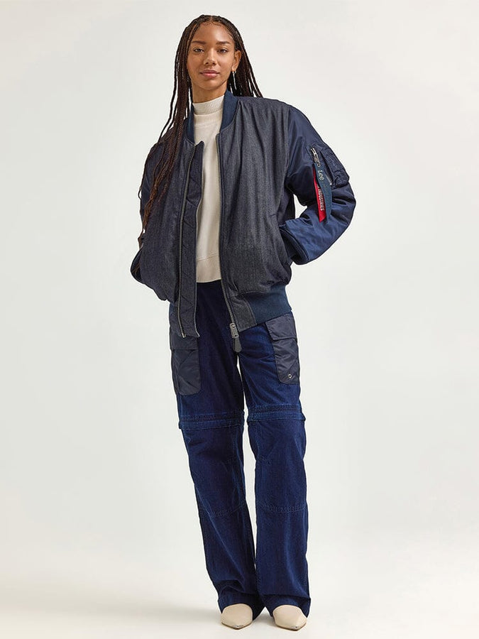 Wearing the Alpha X Lee Reversible MA-1 Jacket by Alpha Industries over a white turtleneck, paired with dark cargo pants and cream shoes, the person exudes a contemporary style infused with vintage railroad-stripe influences.