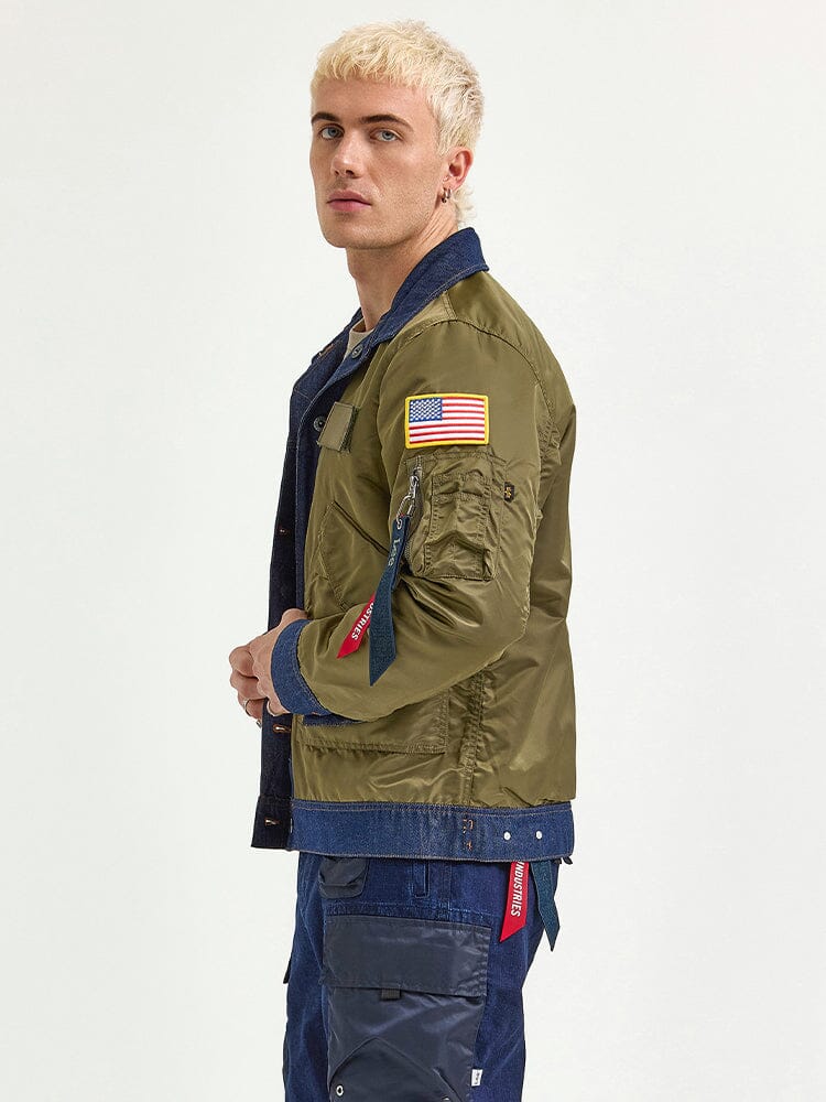 The individual is wearing an Alpha Industries Alpha X Lee Reversible Rider Jacket featuring a U.S. flag patch on the sleeve, paired with blue denim pants, and glancing over their shoulder.