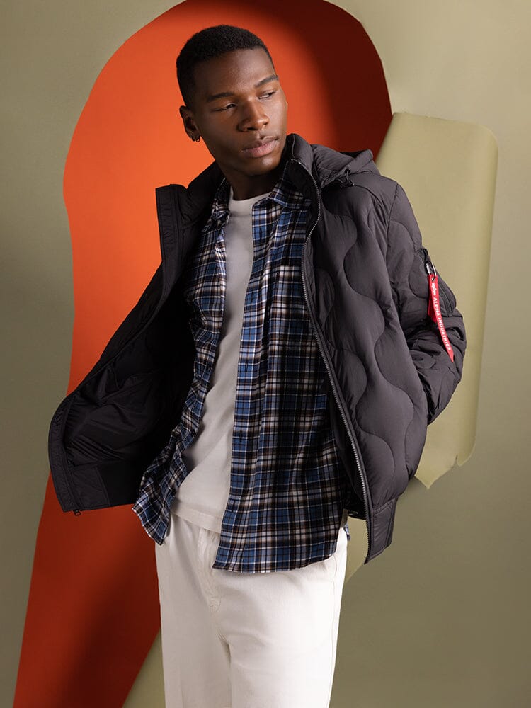A person wearing an Alpha Industries Lightweight Quilted Down Jacket in black.