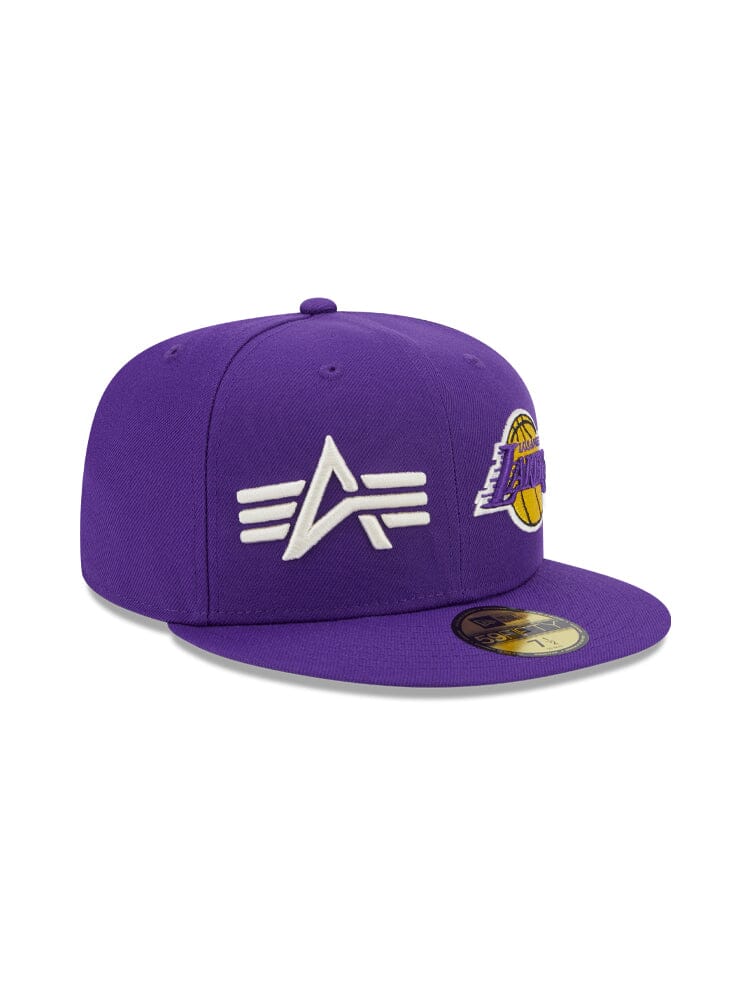 The Los Angeles Laker X Alpha X New Era 59Fifty Fitted Cap from Alpha Industries and NE-NBA showcases a purple design with a white embroidered A team logo on the front and a yellow basketball logo on the side, effortlessly combining style with sporty appeal.