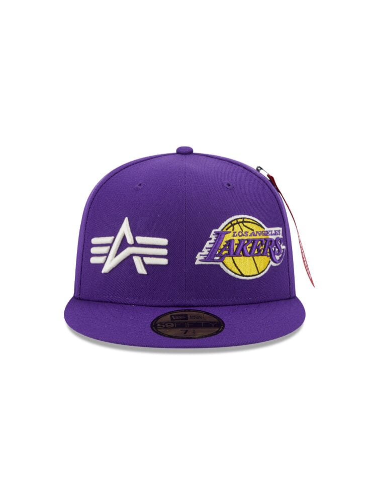 The Los Angeles Laker x Alpha x New Era 59Fifty Fitted Cap, from Alpha Industries and NE-NBA, is a purple hat showcasing white embroidery of a symbol on the left side and the iconic Los Angeles Lakers team logo on the right.