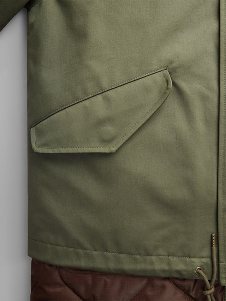 Close-up of the M-65 Long Liner, a green jacket by Alpha Industries, showcasing its NYCO fabrication with a side pocket and an onion quilted lower section for enhanced style.