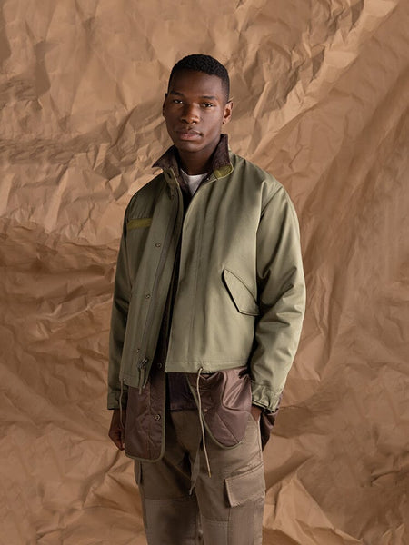 A person wearing the Alpha Industries M-65 Long Liner jacket in OG-107 Green.