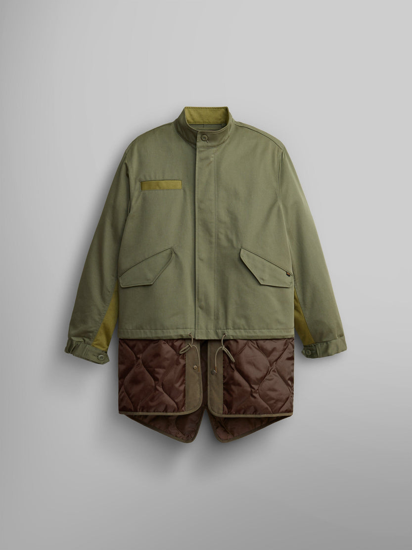 The M-65 Long Liner from Alpha Industries features a high collar and large pockets in OG-107 Green, elegantly displaying an onion quilted lining that extends from the hem.