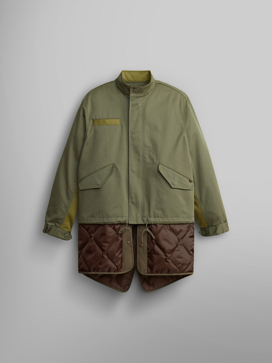 The M-65 Long Liner from Alpha Industries features a high collar and large pockets in OG-107 Green, elegantly displaying an onion quilted lining that extends from the hem.