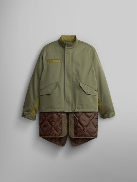 The M-65 Long Liner from Alpha Industries features a high collar and large pockets in OG-107 Green, elegantly displaying an onion quilted lining that extends from the hem.