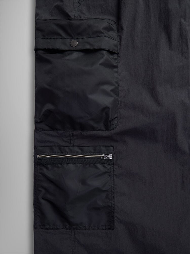 Close-up of the Women's M-65 Skirt by Alpha Industries, showcasing its black military-style design with two cargo pockets: one with a snap-button flap and the other with a zipper.