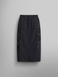 The Women's M-65 Skirt by Alpha Industries in black, a high-waisted cargo skirt that reaches knee-length. It features side cargo pockets and a button closure along with an adjustable waistband.