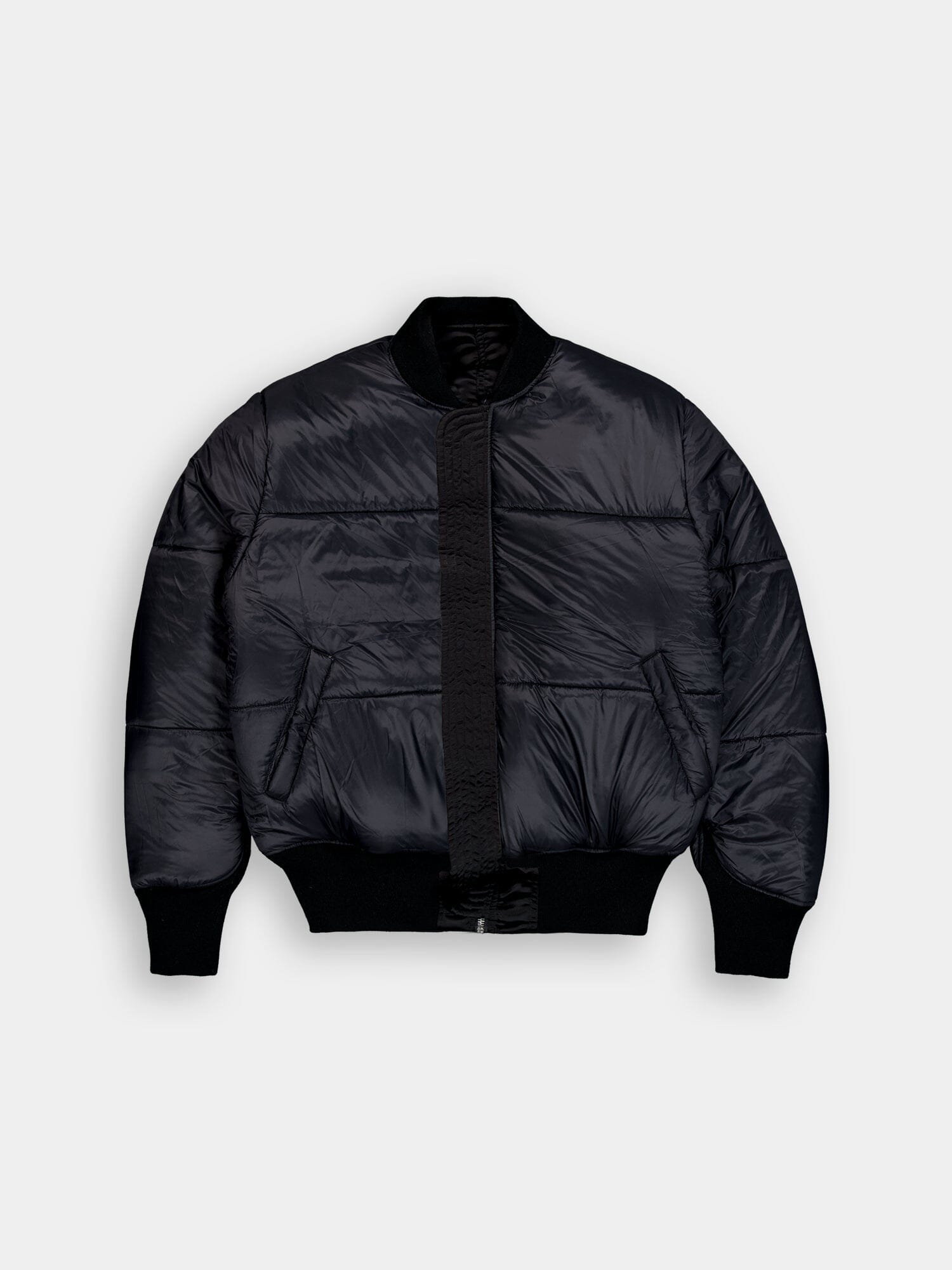 Alpha Industries MA-1 jacket in black with puffer-style bomber design, ribbed cuffs and hem, front zipper closure, and side pockets.