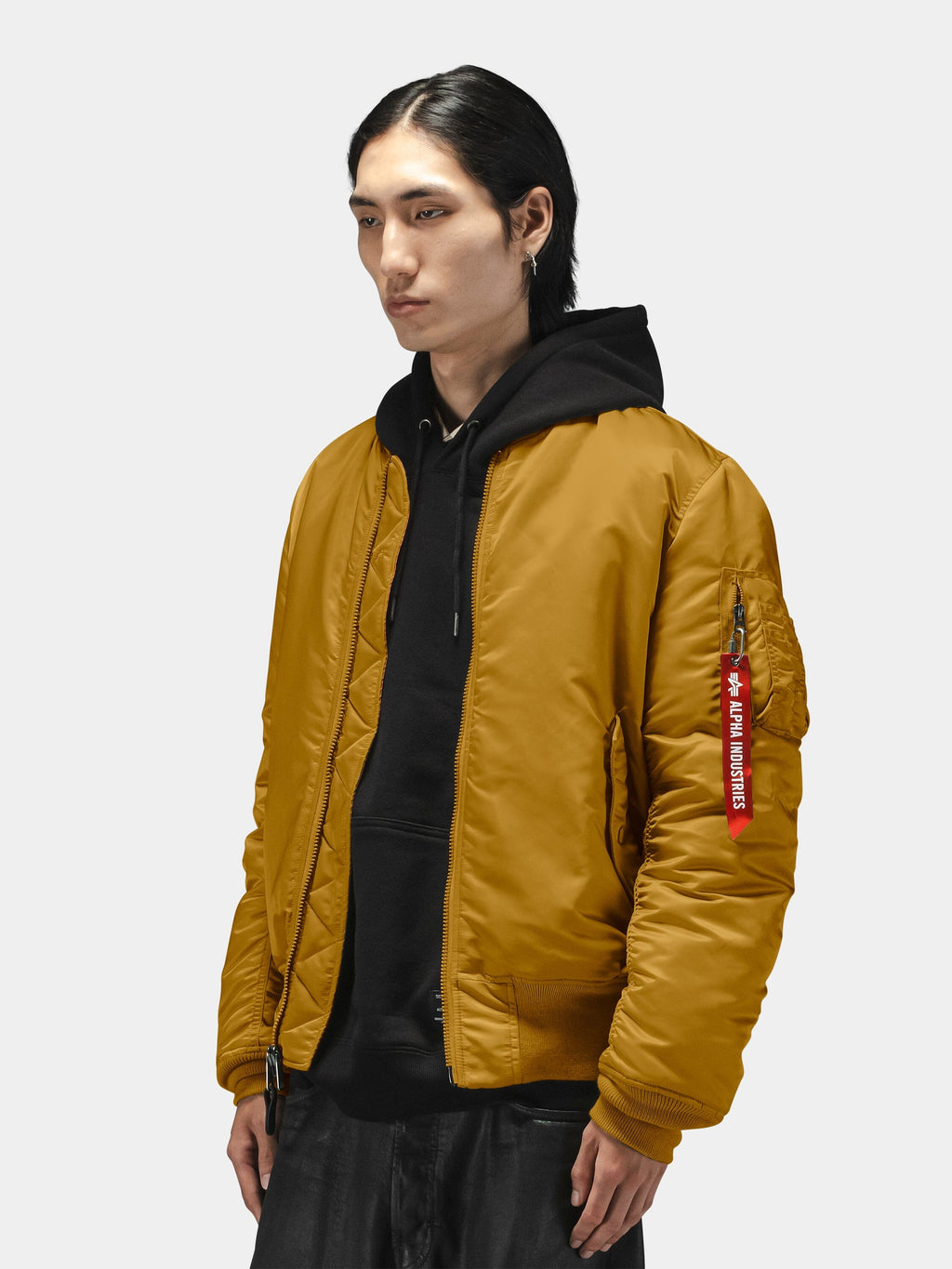 Alpha Industries MA-1 Bomber Jacket in mustard yellow over a black hoodie, featuring nylon material and zip closure.