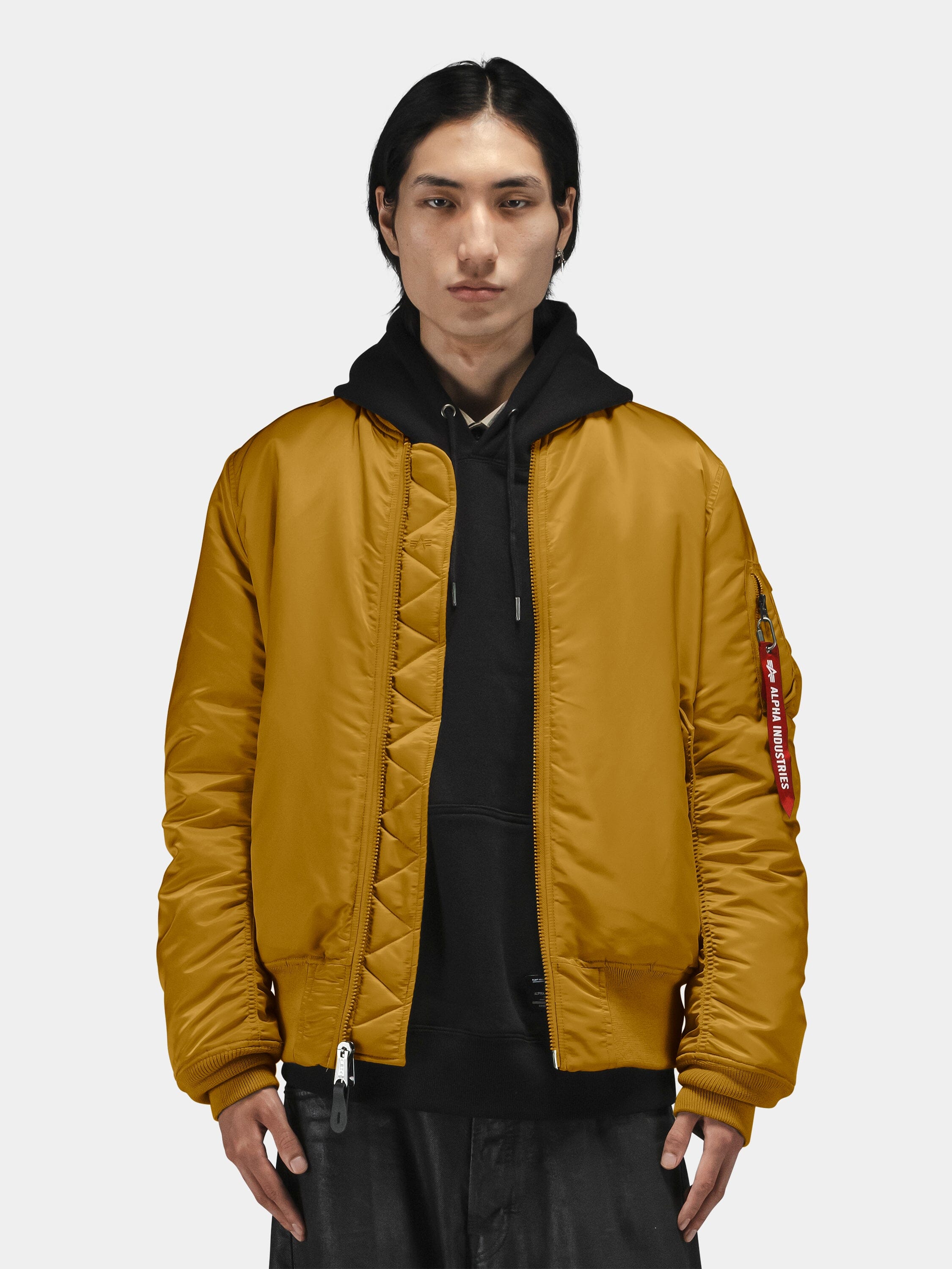 Mustard yellow Alpha Industries MA-1 Bomber Jacket over black hoodie, featuring ribbed cuffs and zip closure.