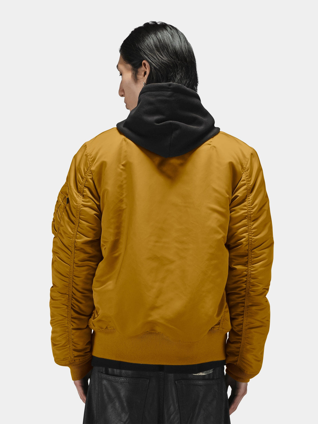 Alpha Industries MA-1 Bomber Jacket in mustard yellow over a black hooded sweatshirt.