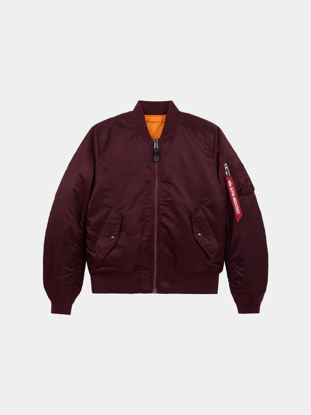 Front flat-lay view of cedar red Alpha Industries MA-1 Bomber Jacket Slim Fit showing ribbed collar, sleeve pocket with red tag, and orange lining at collar.