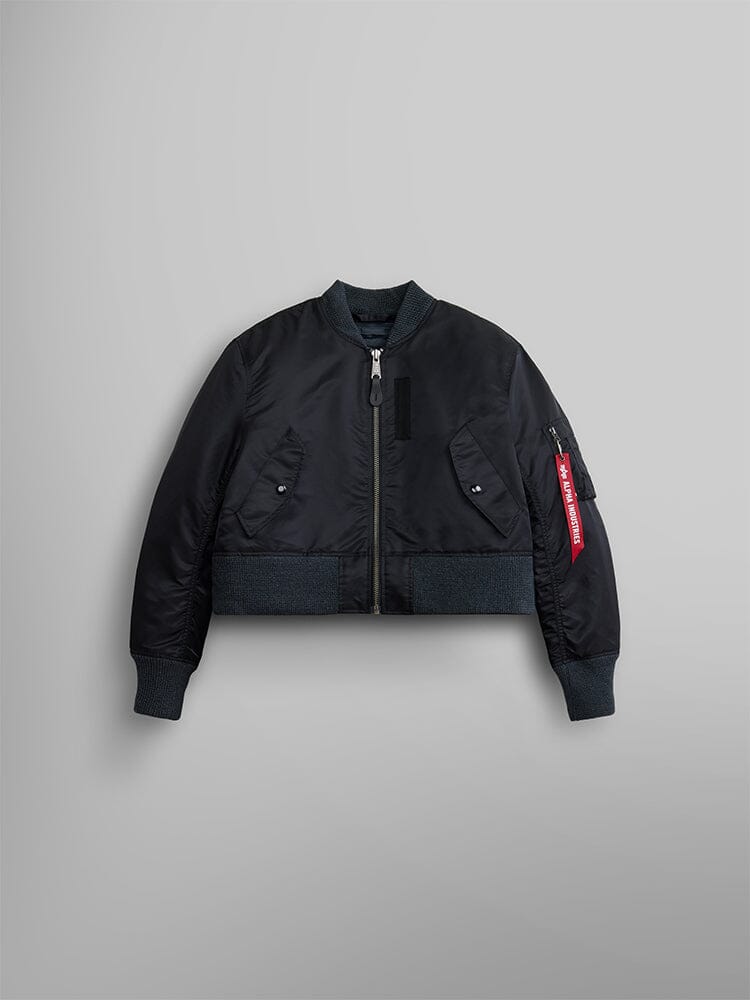 The Women's 3-in-1 MA-1 Quilted Liner by Alpha Industries features a black bomber jacket with a zip-up front, ribbed cuffs and hem, and a distinctive red tag on the left sleeve.