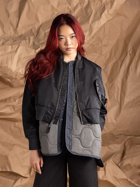 A person models the Women's 3-in-1 MA-1 Quilted Liner by Alpha Industries, showcasing a cropped outer jacket layered over an onion quilted liner.