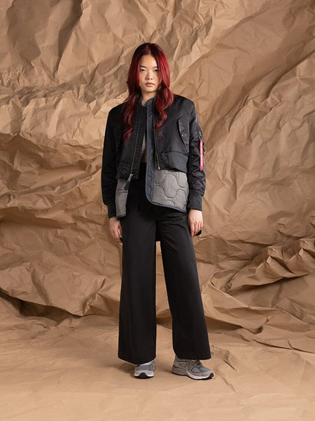 A person wearing the Women's 3-in-1 MA-1 Quilted Liner by Alpha Industries, styled with a cropped outer jacket and wide-leg pants.