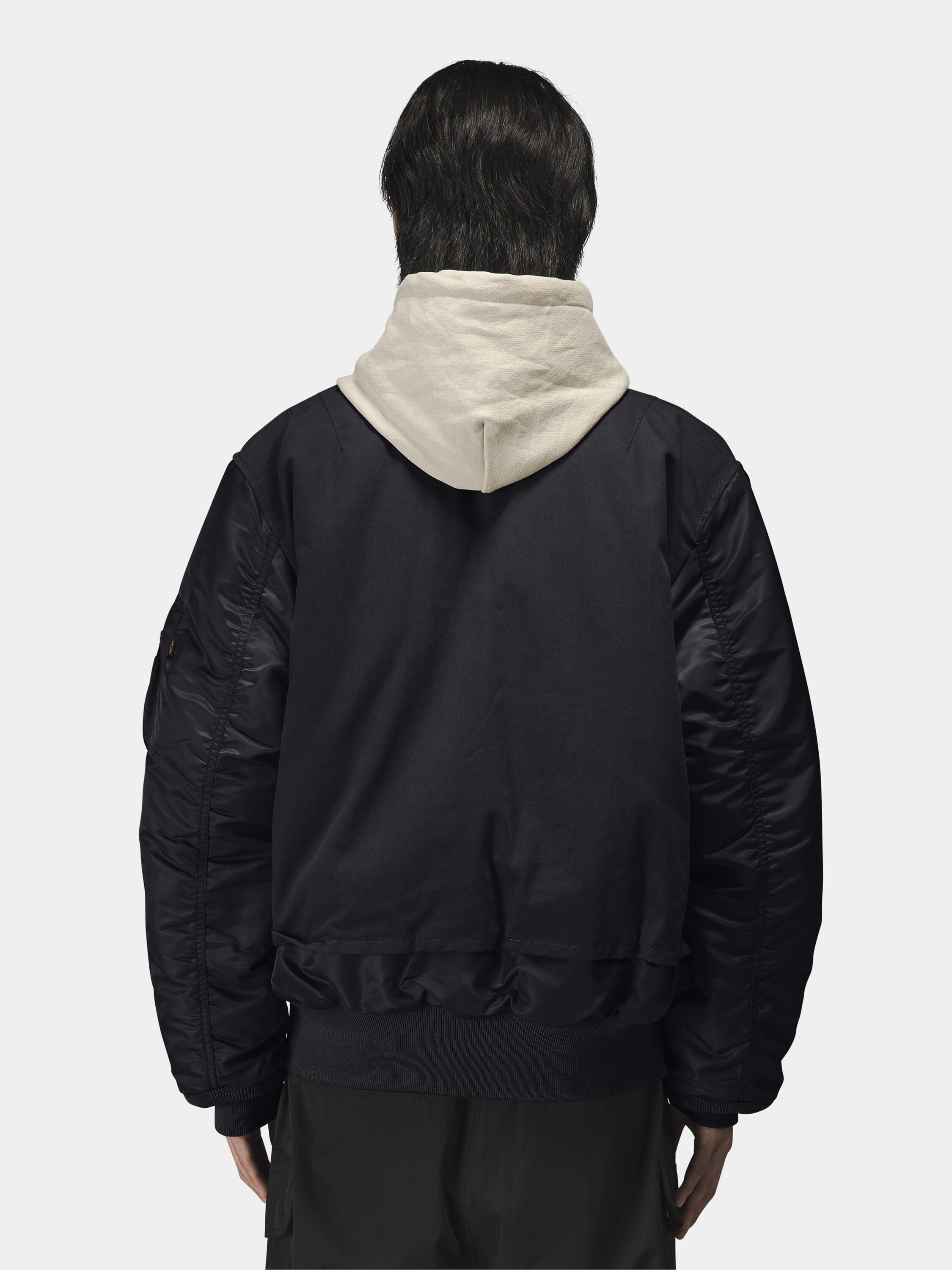 Alpha Industries MA-1 Mixed Cotton Flight Jacket in black, layered over light-colored hoodie.