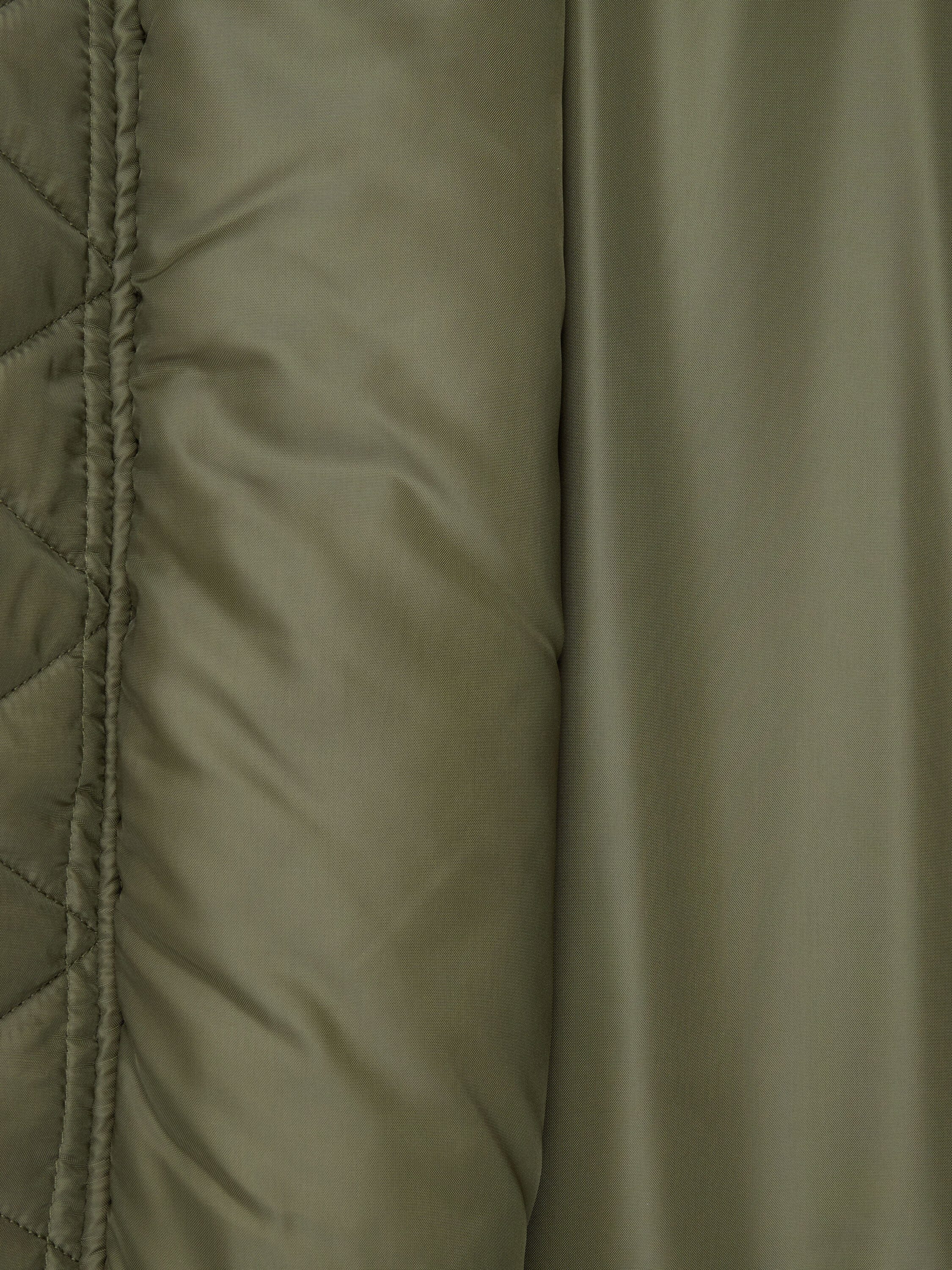 Olive green quilted fabric and smooth, slightly shiny surface of the Alpha Industries MA-1 Oxford Flight Jacket.