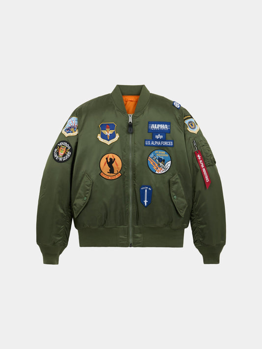 Alpha Industries MA-1 Squadron Bomber Jacket in sage with squadron patches and a red Remove Before Flight tag on the left sleeve.