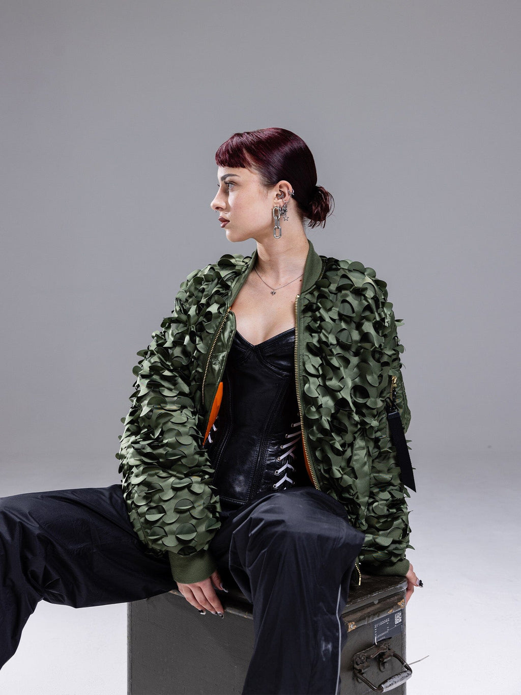 Alpha Industries MA-1 ULCANS Flight Jacket in textured green, black outfit visible under jacket.