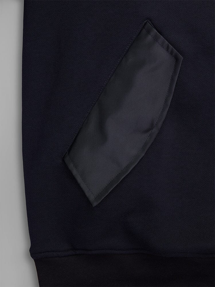 Close-up of a fabric patch pocket on the MA-1 Zip Up Hoodie by Alpha Industries. The pocket is crafted from black French terry fabric, showcasing its texture and stitching details on this dark garment.