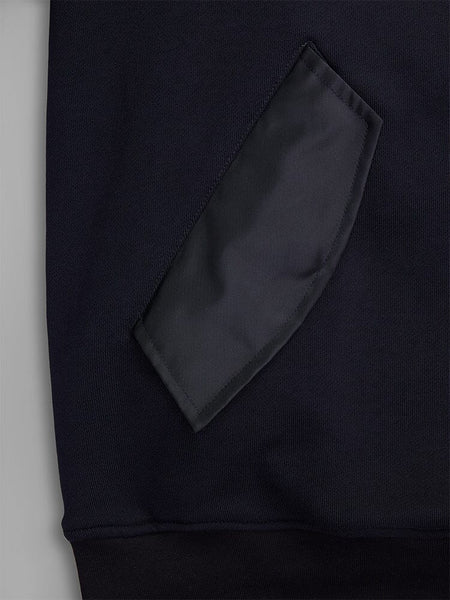 Close-up of a fabric patch pocket on the MA-1 Zip Up Hoodie by Alpha Industries. The pocket is crafted from black French terry fabric, showcasing its texture and stitching details on this dark garment.