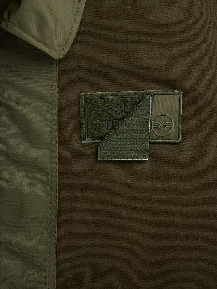 Alpha Industries Mixed Media CWU 36P Mod Jacket, olive green patch with Velcro flap, partially open to show brand name and logo.