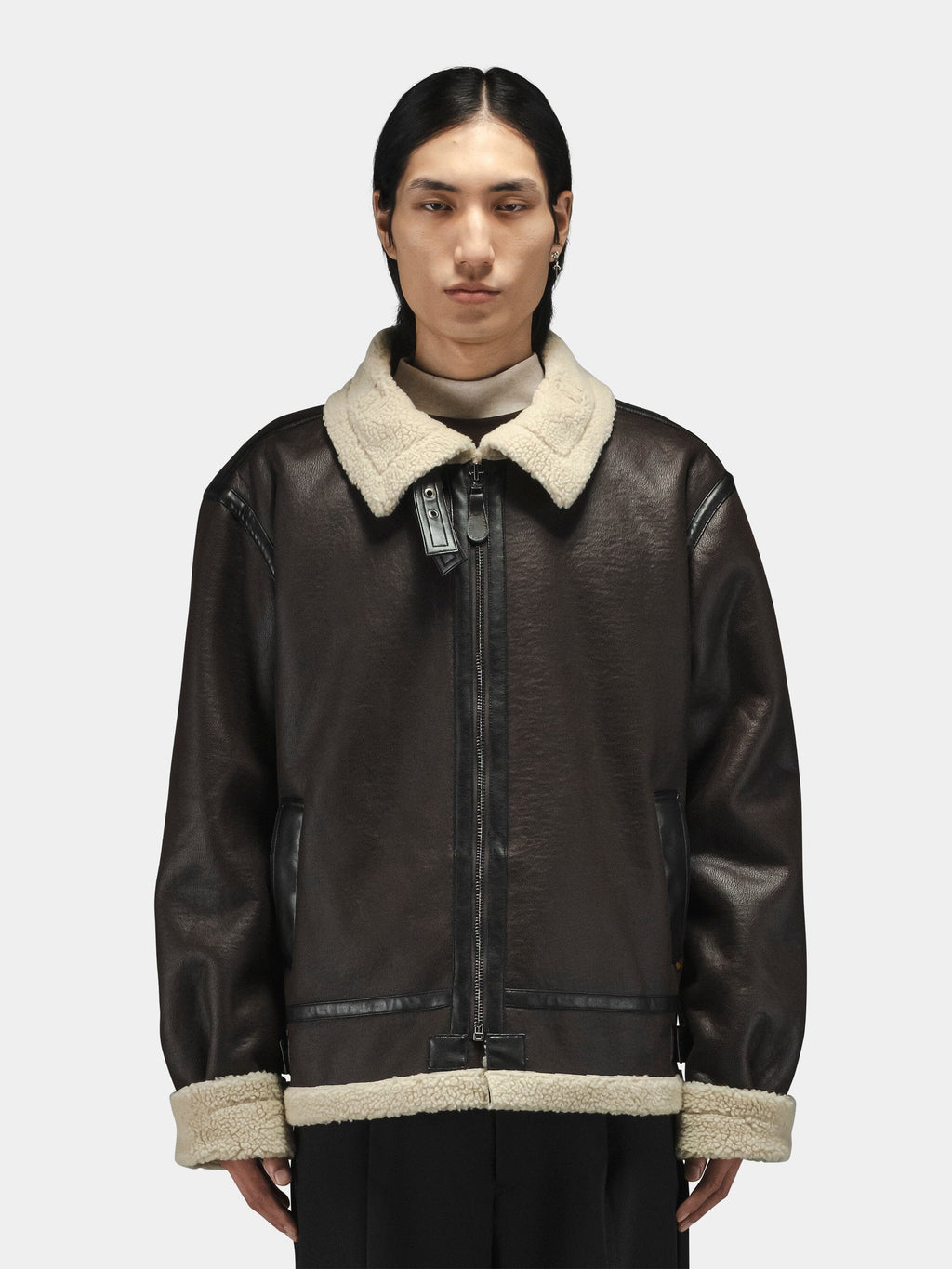 Alpha Industries Mouton B-3 aviator jacket in dark brown with light beige collar and cuffs, layered over a high-neck top.
