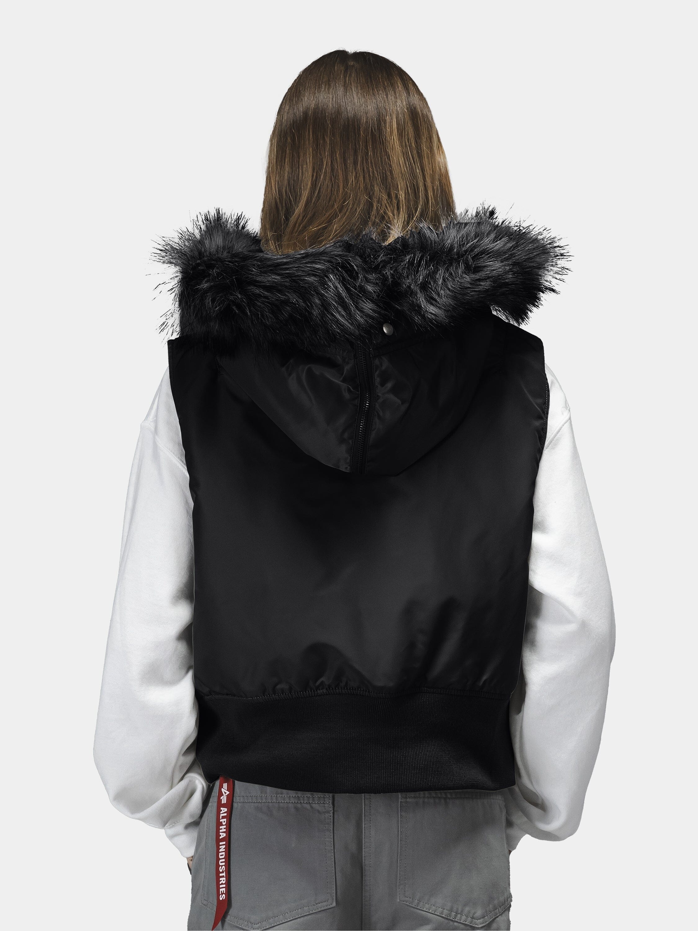 Alpha Industries N-2B Vest Womens in black with faux fur hood, white long-sleeve shirt, gray pants with red tag.