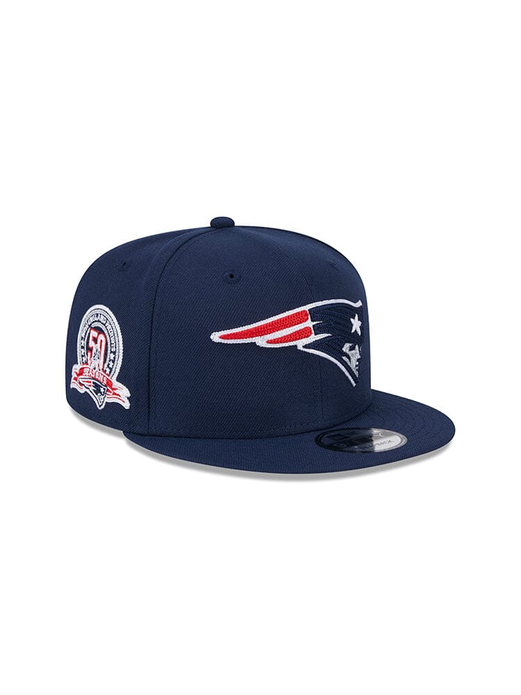 The New England Patriots X Alpha Industries X New Era 950 Cap is a navy blue snapback baseball cap showcasing a multicolor emblem on the front and a 100th season logo on the side.