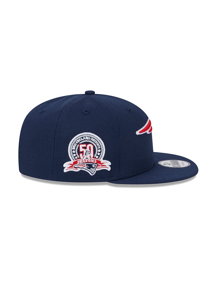 The New England Patriots x Alpha x New Era 950 Cap, crafted by Alpha Industries, combines a modern navy design with the New England Patriots logo and a commemorative 50 seasons patch on the side, finished with a sleek snapback closure for an ideal fit.