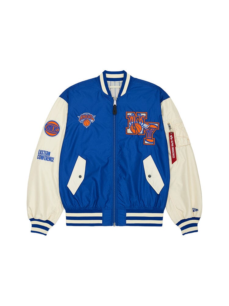 The New York Knicks X Alpha X New Era L-2B Bomber Jacket from Alpha Industries is a stylish blue piece adorned with New York Knicks logos and team patches. It features a front zipper and two pockets, perfectly capturing the spirit of the game through this classic collaboration.