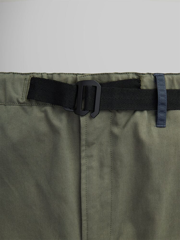 Close-up of the olive-green Oversized Tactical Pant by Alpha Industries, highlighted by a black belt with a rectangular buckle. This piece features a visible seam down the middle, adding structure to its relaxed fit.